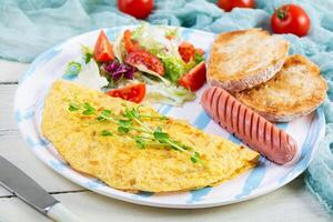 Fried omelette with sausage and salad. Delicious breakfast with eggs and toast photo