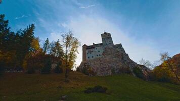 Famous Count Dracula castle on the hill among the colorful trees. Low angle view. Autumn in Romania. video