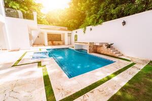 Homemade swimming pool surrounded by trees. Beautiful crystal clear swimming pool in a backyard. Concept of domestic swimming pool designs photo