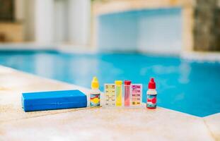 Water test kit on the edge of the swimming pool. Chlorine test kit for swimming pools. Chlorine and ph tester for swimming pools photo