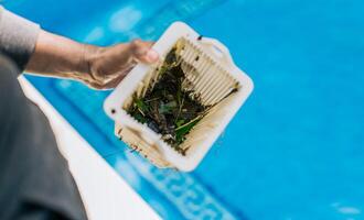 Man cleaning garbage filter basket for swimming pool. trash. Hand holding swimming pool filter basket photo