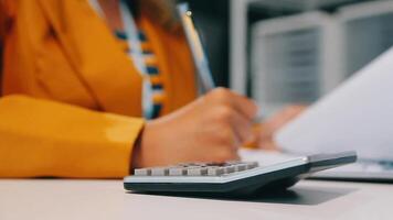 Close up Business woman using calculator and laptop for do math finance on wooden desk in office and business working background, tax, accounting, statistics and analytic research concept video