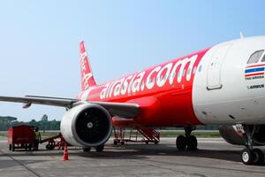 SAKONNAKHON, THAILAND - APRIL 24, 2024, Side view of airplane A320 of Thai AirAsia The plane is parked on airstrip runway tarmac to prepare its engines and loading baggage onto the plane. photo