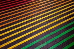 Colorful lines on the black floor and walkway. Crossing the street on a multi colored crosswalk painted with the colors of the pride flag. Rainbow color. photo
