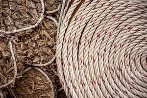 White rope with red lines and coiled roll from top view on wooden table background in warm tone. Braided rope on a roll background texture 2025. Photo of an old vintage rope.
