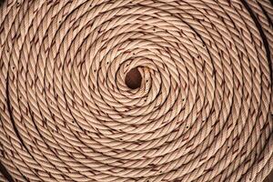 Brown rope with red lines and coiled roll from top view on wooden table background in warm tone. Braided rope on a roll background texture 2025. Photo of an old vintage rope.