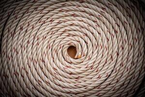 White rope with red lines and coiled roll from top view on wooden table background in warm tone. Braided rope on a roll background texture 2025. Photo of an old vintage rope.