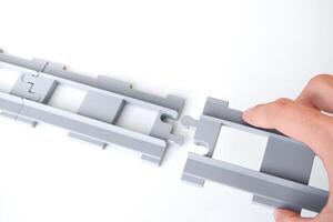 Hand holding gray toy railroad tracks put on a white background. Hand holding the tpy railroad tracks to connect them together for the concept of connection and disconnect. photo