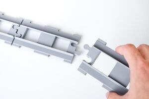 Hand holding gray toy railroad tracks put on a white background. Hand holding the railroad tracks to connect them together for the concept of connection and disconnect. photo