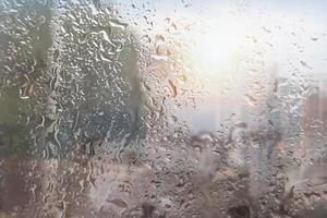 Rain falls on the window with a blurred background. Indicates a rainy day photo