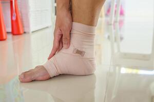 Man with ankle sprain elastic bandage for ankle injury and feeling pain photo