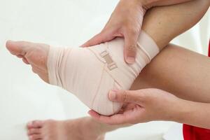 Man with ankle sprain elastic bandage for ankle injury and feeling pain photo