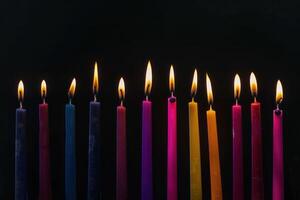 A set of lit Hanukkah candles lined up. In the form of dark, foreboding, contrasting colors. photo