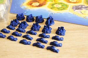 A catan board game neatly arranged blue player figure chips. Preparing for the game photo