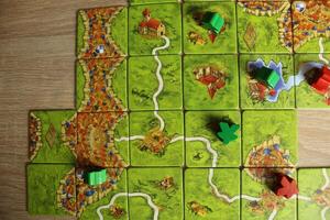 green and red meeples lie on the map in the game carcassonne top view photo