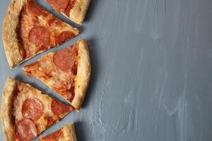 Border of pepperoni slices of pizza with cheese and sausage on a gray background with space for text Copyspace Upper angle photo