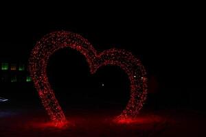 Christmas Figure Illumination Red Heart at Night. Festive atmosphere neon photo zone