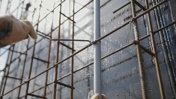 A worker twists metal reinforcement with wire at the construction site video