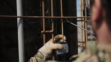A worker twists metal reinforcement with wire at the construction site video