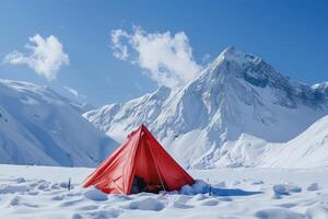 A red tent set against a backdrop of vast snowy mountains under a clear blue sky. photo