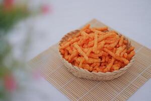 Crispy Corn Puffs in rattan basket on bamboo mat. Selective focus. photo