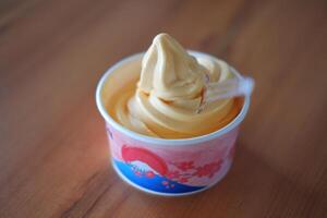 ice cream in paper cup on wood table background. soft focus. photo