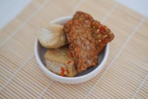 Fried tofu and tempeh in white bowl on bamboo tablecloth background. photo