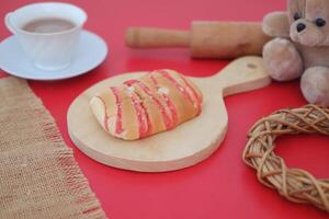 Strawberry bread with tea and teddy bear on red background photo