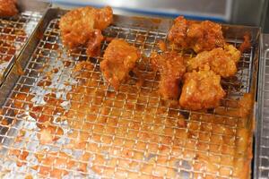 crispy fried chicken pieces coated with a reddish sauce resting on a metal wire rack photo