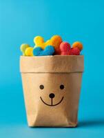 colorful heart-shaped candies in a paper bag with a smiling face on a blue background. photo