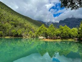 Serene mountain lake with lush greenery and cloudy sky reflection. photo