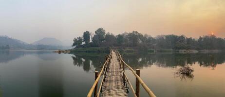 Bamboo Bridge Over Serene Lake at Sunset. photo