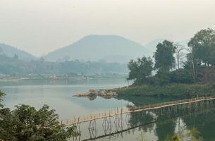 Bamboo Bridge Over Serene Lake at Sunset. photo