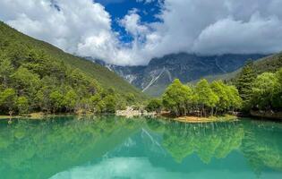 Serene mountain lake with lush greenery and cloudy sky reflection. photo