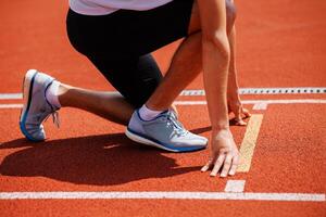 A track runner is standing at the starting line, getting ready for a quick sprint photo