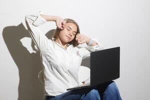 tired girl at a table with a laptop on a white background photo
