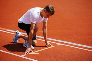 A track runner is standing at the starting line, getting ready for a quick sprint photo