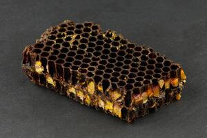 Bee pollen in honeycomb. Bee bread isolated on a black background. photo