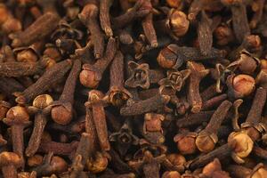 Clove spice pile close up. Dry spice cloves background and texture, top view photo