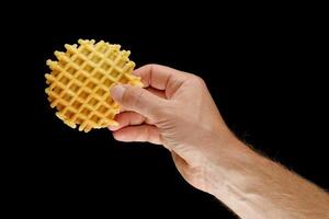 Belgian waffles in hand on black isolate photo