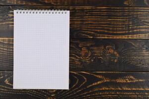 Notebook with cells on a wooden background. empty notebook on wooden table, top view photo