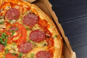 pizza in box open. Pizza in the in delivery box against a dark background photo