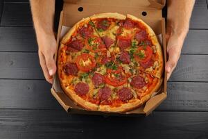 pizza in box open. Pizza in the in delivery box against a dark background photo