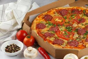 Pizza in a box on the table. Hot pizza with vegetables. Pizza in a restaurant. photo
