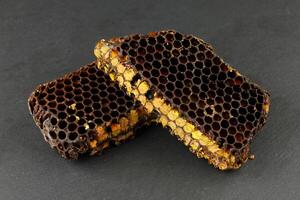 Bee pollen in honeycomb. Bee bread isolated on a black background. photo