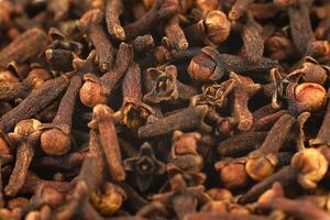 Clove spice pile close up. Dry spice cloves background and texture, top view photo