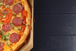 Pizza with salami and tomatoes in a box. place for text cope space photo