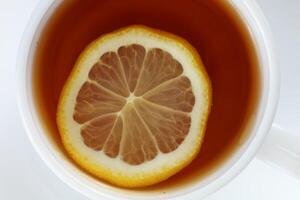 Tea with lemon in a white cup close-up. A slice of lemon in a cup of tea photo