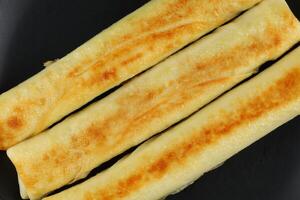 Pancakes rolls on a black plate. photo