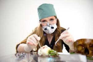 Operation on the layout . Young woman learning to operate on a flower on a rose using a scalpel and an injection photo